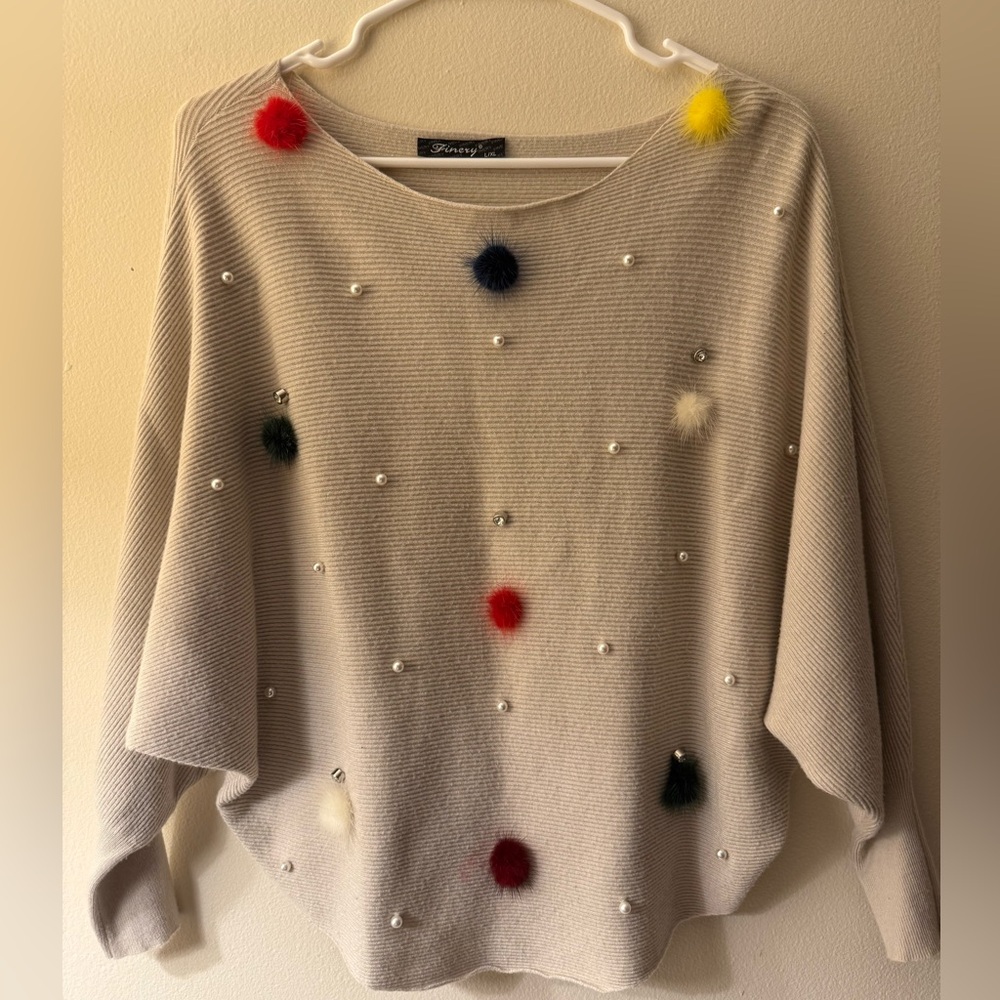 Elegant Cream Sweater with Colorful Pom Pom Accents.